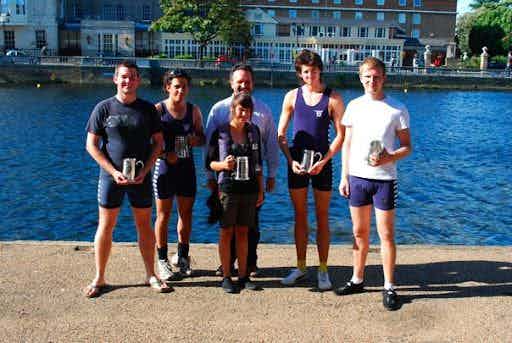 The successful coxed four, holding their pots by the river. 